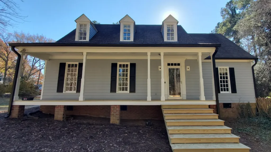 The front of a house after painting with gray colored siding and black shutters.