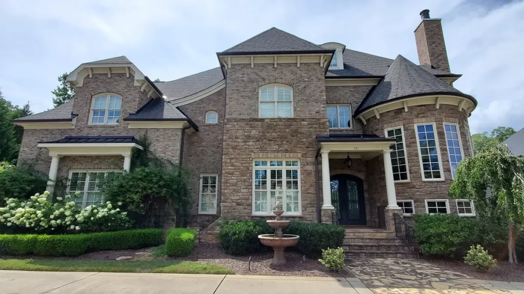 A freshly painted house in Cary, NC with stone and cream trim completed by A Touch of Color Painting & General Contracting.