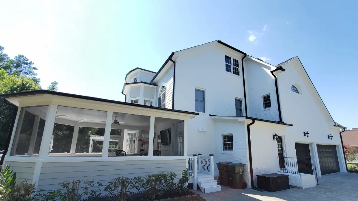 Modern white brick house exterior painted by A Touch of Color with contrasting black gutters in Cary, NC.