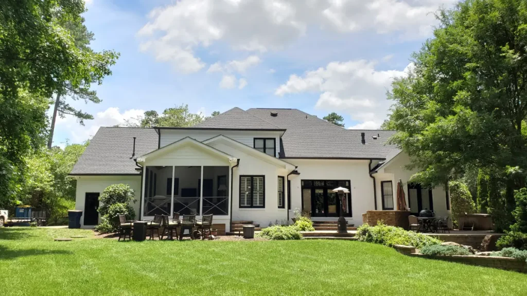 Modern white brick backyard exterior with contrasting black gutters, creating a premium outdoor living space for a residential home in Wake Forest, NC.