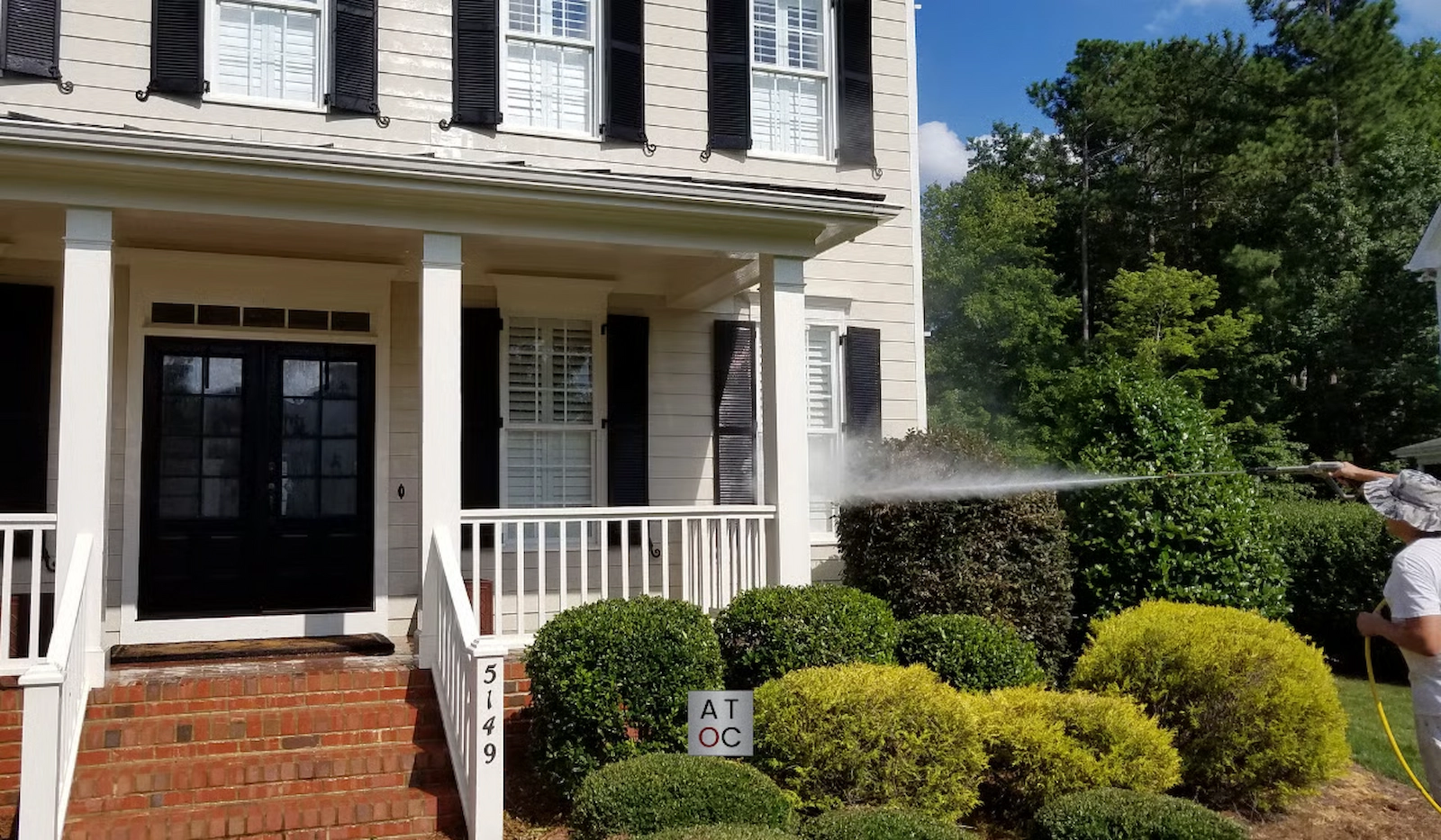 A Touch of Color employee washing a house utilizing a soft wash before exterior painting. A Touch of Color employee washing a house utilizing a soft wash before exterior painting.