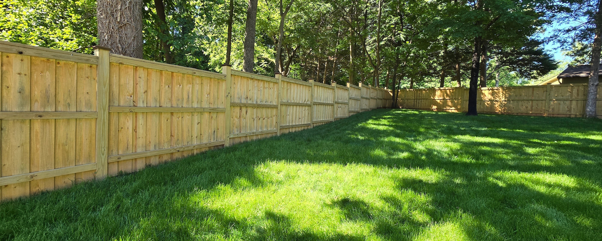 Newly installed treated wood fence preparation and staining.